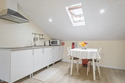 a kitchen with white cabinets and a table with flowers on it at Eyes in the Sky in Funchal