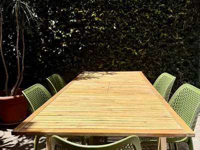 a wooden table with green chairs around it at Vila Luis Mendes in Ribeira Brava