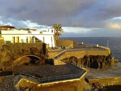 a building on a cliff next to the ocean at Beach Flat - Apartamento Praia Doca do Cavacas in Funchal
