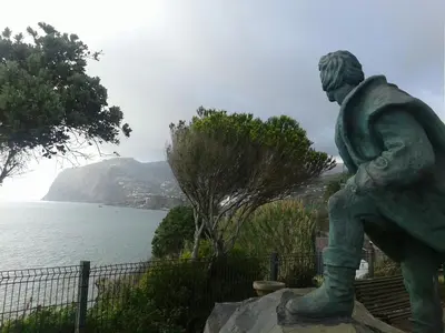 a statue of a man standing on a rock near the water at Beach Flat - Apartamento Praia Doca do Cavacas in Funchal
