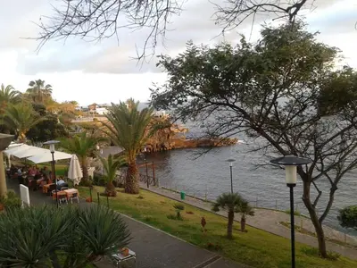 a view of a body of water with people sitting at tables at Beach Flat - Apartamento Praia Doca do Cavacas in Funchal