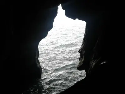 a person in a cave looking out at the ocean at Beach Flat - Apartamento Praia Doca do Cavacas in Funchal