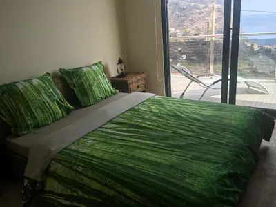 a bedroom with a green bed with a large window at Guesthouse-TheView in Ribeira Brava