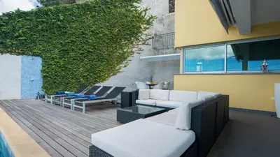a deck with couches and chairs on a building at Estrela do Mar - by LovelyStay - Lovely, Sun Filled Villa in Calheta