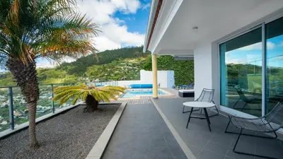 a house with a balcony with a palm tree and a pool at Estrela do Mar - by LovelyStay - Lovely, Sun Filled Villa in Calheta
