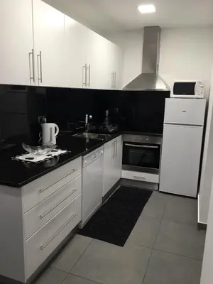 a kitchen with white cabinets and white appliances at Villa Por do Sol in Estreito da Calheta
