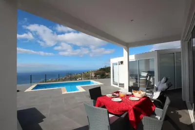 a dining room with a table and a view of the ocean at Villa Por do Sol in Estreito da Calheta
