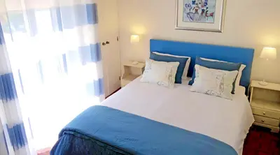 a bedroom with a large bed with a blue headboard at CHIQUITA PLACE, Praia da Luz in Luz