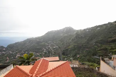 a view of a mountain with houses and the ocean at Lobos Rustic House II in Câmara de Lobos