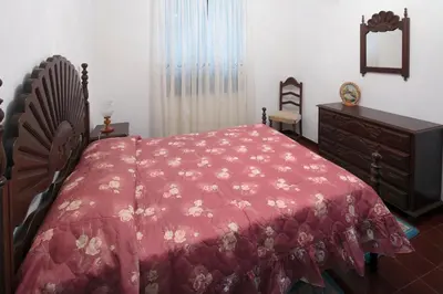 a bedroom with a red bed and a dresser at Lobos Rustic House II in Câmara de Lobos