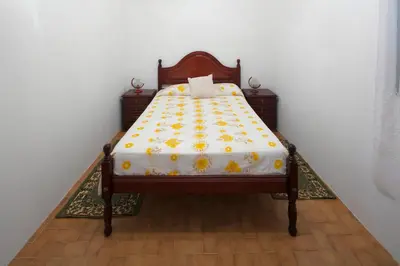 a bed with a yellow and white comforter on it at Lobos Rustic House II in Câmara de Lobos
