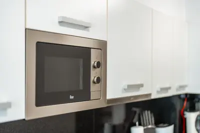 a microwave oven in a kitchen with white cabinets at Central Sea View by Amazing Madeira in Funchal