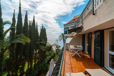 a balcony of a building with a table and trees at Central Sea View by Amazing Madeira in Funchal