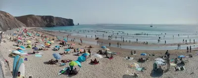 a crowd of people on a beach with umbrellas at Beach&Surf Flat in Aljezur