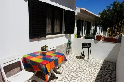 a patio with a table and chairs on a balcony at Casa Lusco Fusco in Carrapateira