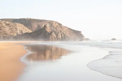 a sandy beach with a mountain in the background at Casa Lusco Fusco in Carrapateira