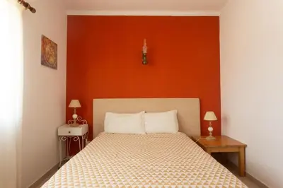 a bedroom with a bed with an orange wall at Casa Lusco Fusco in Carrapateira