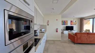 a kitchen and living room with a couch and a television at Eden Sun - A Modern Luxury Villa with a Panoramic View in Prazeres