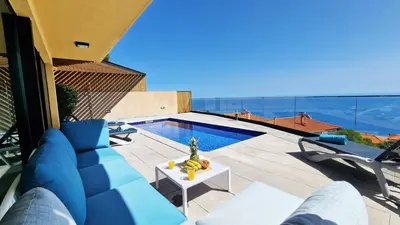 a blue couch sitting on a patio next to a pool at Eden Sun - A Modern Luxury Villa with a Panoramic View in Prazeres