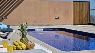 a pineapple sitting on a table next to a swimming pool at Eden Sun - A Modern Luxury Villa with a Panoramic View in Prazeres