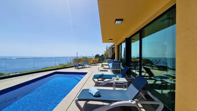 a house with a swimming pool and chairs on a balcony at Eden Sun - A Modern Luxury Villa with a Panoramic View in Prazeres
