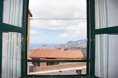 an open window with a view of a building at A Slice of Paradise - Palheiro Golf in Funchal