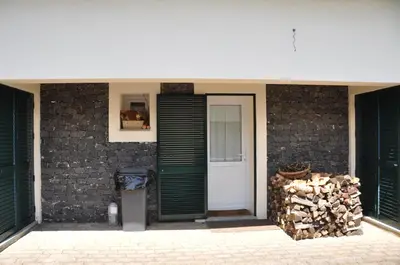 a building with a door and a pile of wood at Luxury VILLA CAMÉLIA. Mountains, golf, horses, levada walks. in Santo da Serra