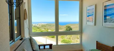 a living room with three windows with a view of the ocean at Sunset View Flat in Aljezur