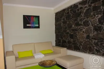 a living room with a couch and a stone wall at Solar do Carvalho in São Vicente
