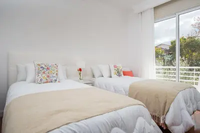 two beds in a white room with a window at Susy’s Garden in Funchal