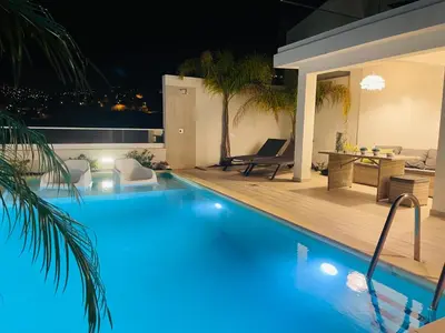 a swimming pool at night with a table and chairs at Susy’s Garden in Funchal