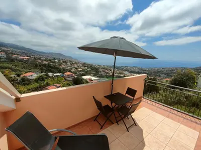 a balcony with a table and an umbrella at Costa Residence Funchal View in Funchal