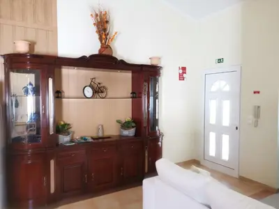 a living room with a wooden cabinet and a white couch at Costa Residence Funchal View in Funchal