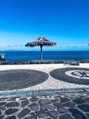 a straw umbrella on the beach near the ocean at TRIPLEX TERRASSE VUE EXCLUSIVE SUR L OCÉAN ,WIFI in Santa Cruz