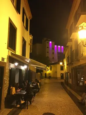 a group of people sitting at tables in an alley at night at TRIPLEX TERRASSE VUE EXCLUSIVE SUR L OCÉAN ,WIFI in Santa Cruz