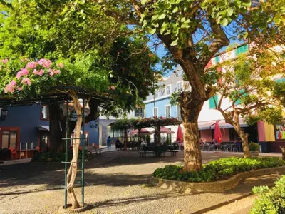 a park with trees and tables and chairs and a building at TRIPLEX TERRASSE VUE EXCLUSIVE SUR L OCÉAN ,WIFI in Santa Cruz