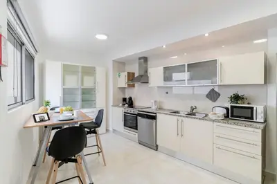 a kitchen with white cabinets and a table and chairs at Santa Catarina II by An Island Apart in Funchal