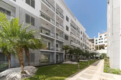 an apartment building with a palm tree in front of it at Santa Catarina II by An Island Apart in Funchal