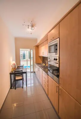 a kitchen with wooden cabinets and a dining table at Funchal Arcadas Apartment by MLV in Funchal