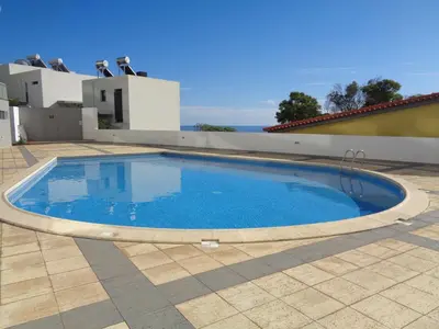 a swimming pool on a patio with a house at Paradisus Stylish Family Living in a 3-Bedroom Condo with Pool in Caniço
