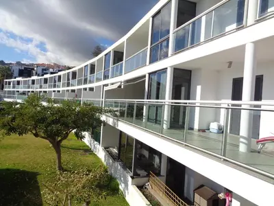 an apartment building with balconies and a tree at Paradisus Stylish Family Living in a 3-Bedroom Condo with Pool in Caniço