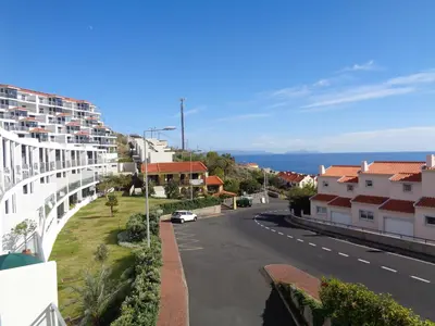 a view of a street with houses and the ocean at Paradisus Stylish Family Living in a 3-Bedroom Condo with Pool in Caniço