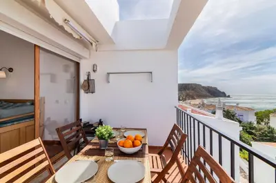 a balcony with a table and chairs and a view of the ocean at H&H seaview in Luz