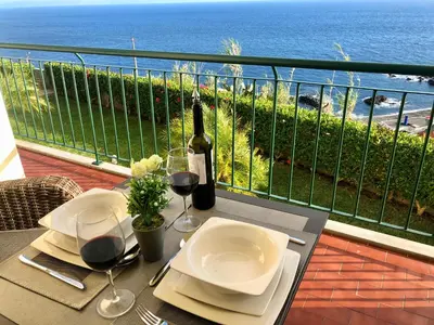 a table with a bottle of wine and glasses on a balcony at Oceanic Apartment in Caniço