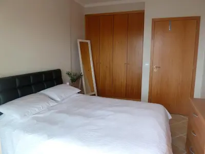 a bedroom with a large white bed with a wooden closet at Oceanic Apartment in Caniço