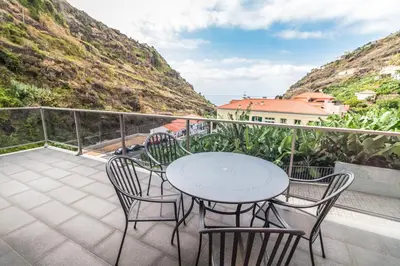 a patio with a table and chairs on a balcony at Pink House - Tabua (Ribeira Brava) in Ribeira Brava