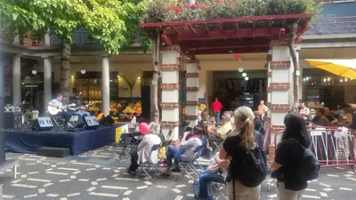 a group of people sitting in chairs watching a man playing music at Top Floor in City Center Funchal in Funchal