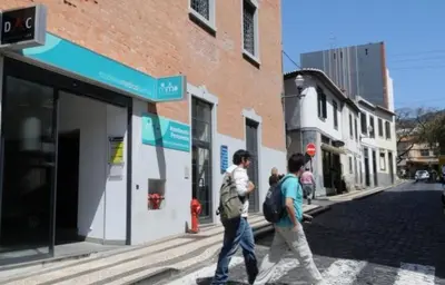 two people walking down a street in front of a building at Top Floor in City Center Funchal in Funchal