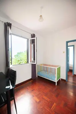 a room with a crib and a large window at Casa reizinho in Santana