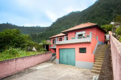 a red house with a garage and a mountain at Casa reizinho in Santana